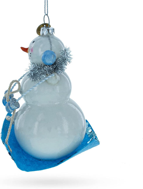 Snowman Riding a Sled Blown Glass Christmas Ornament...