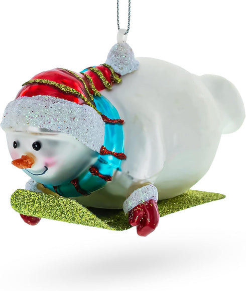 Snowman Gleefully Riding a Sled Glass Christmas Ornament...