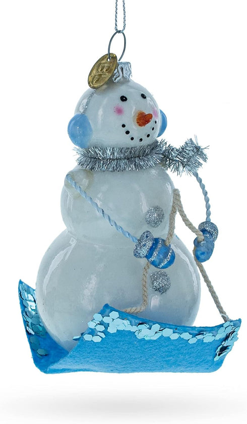 Snowman Riding a Sled Blown Glass Christmas Ornament...